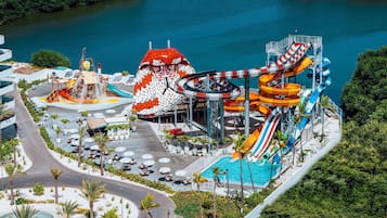 Un parque acuático con múltiples toboganes y piscinas, rodeado de palmeras y zonas de estar al aire libre.