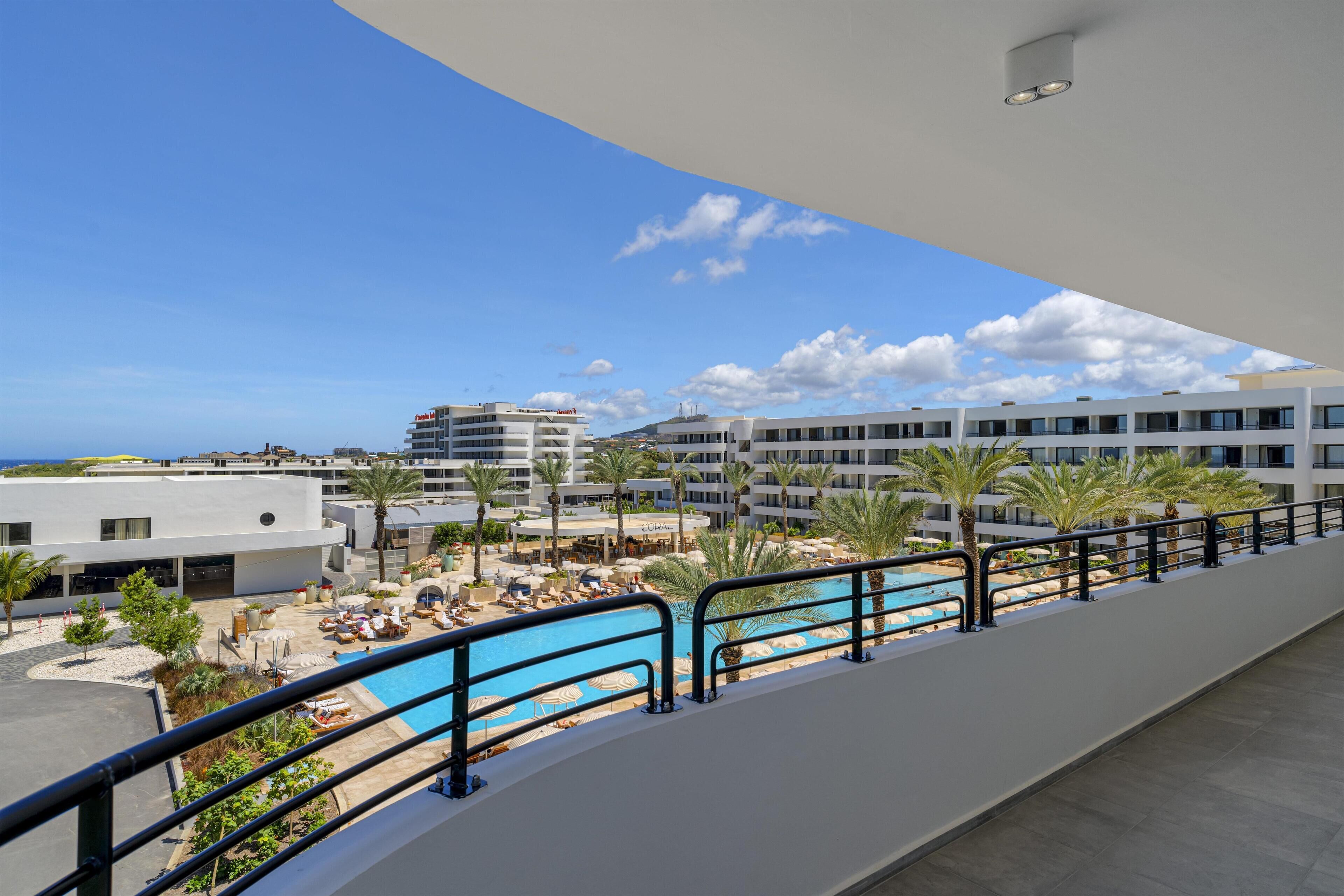 Un resort con piscina, palmeras y vistas al mar.