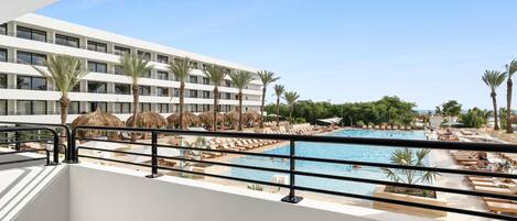 A hotel with a pool area, including sun loungers and umbrellas, and a view of the pool from a balcony.