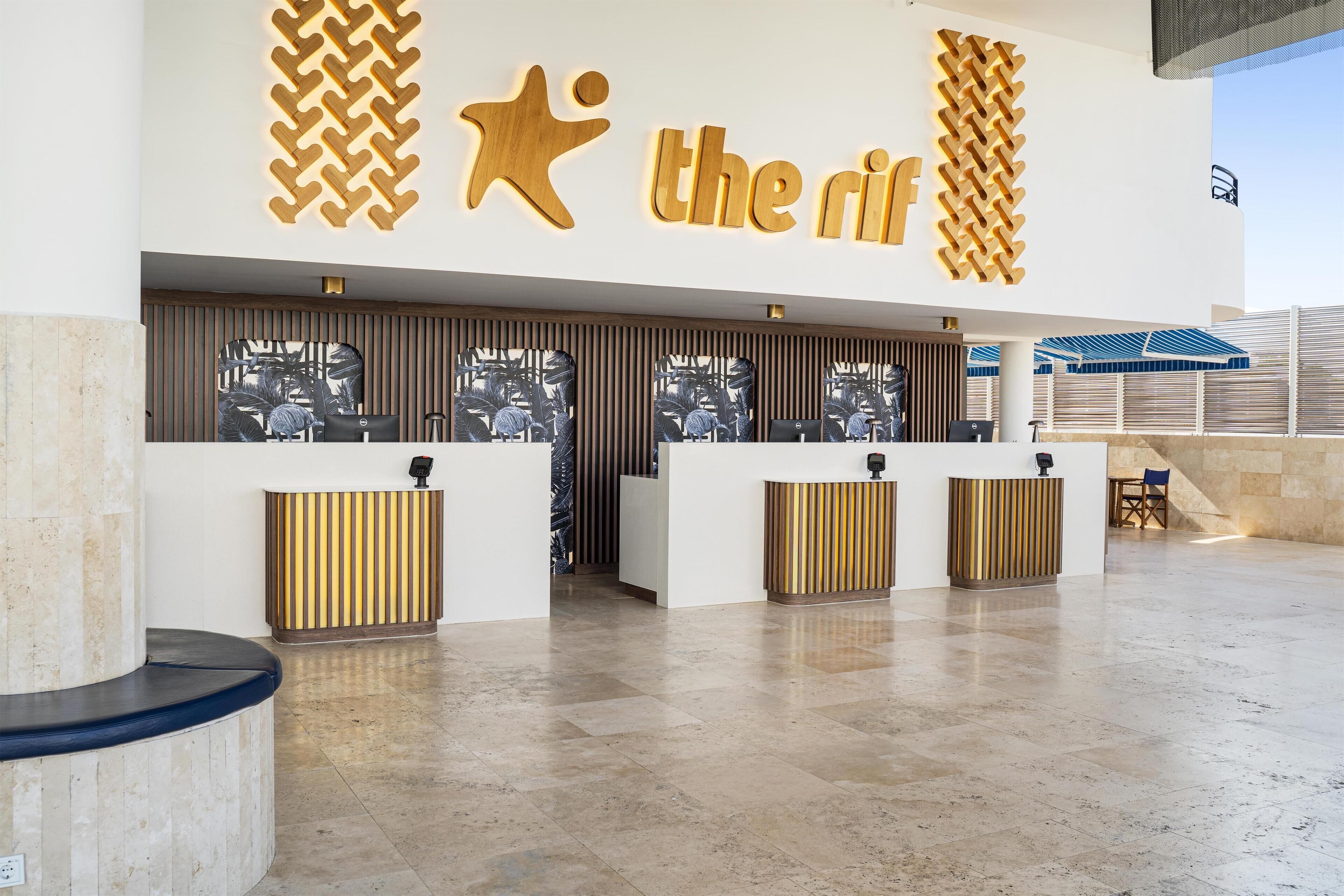 A hotel reception area with a modern design, featuring a large logo and reception desks.