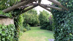 A garden with a wooden fence, lush greenery, and a clear pathway leading to a grassy area. - Brewers Cottage (Umberleigh)