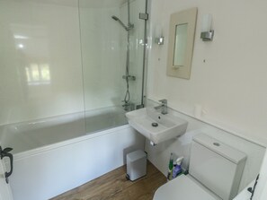Uma casa de banho moderna com cabine de duche em vidro, lavatório branco e sanita.
