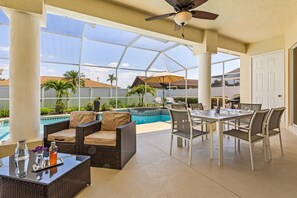 Un espace extérieur aménagé avec une terrasse, une piscine, des meubles en osier et une table à manger.