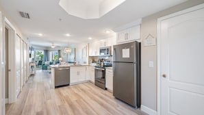 A modern kitchen with white cabinetry, stainless steel appliances, and a wooden floor. - AMAZING BEACH VIEW/ FULLY REMODELED CONDO/ALL NEW FURNITURE/ HEATED POOL (Treasure Island)