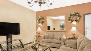 A living room with a television, two couches, a glass coffee table, and two lamps. - Meridian Inn (Meridian)