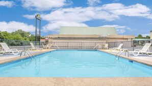 A swimming pool with lounge chairs and a building in the background. - Meridian Inn (Meridian)