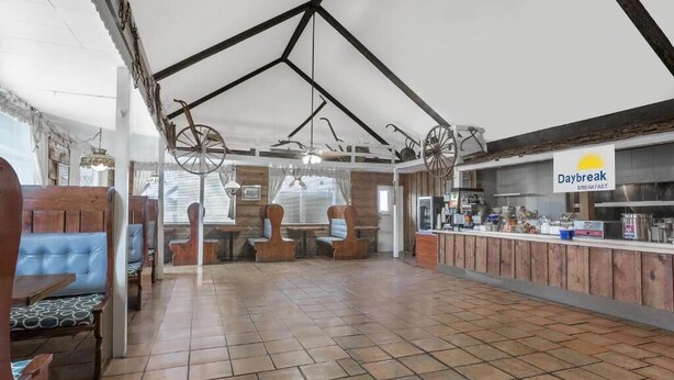 A restaurant with wooden booths, a counter with a sign reading "Daybreak Breakfast," and a tiled floor. - Meridian Inn (Meridian)