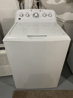A front view of a white front-loading washing machine with control knobs for temperature, load size, and options.