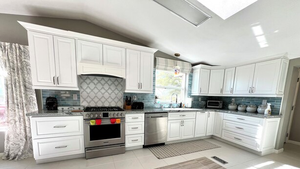 A modern kitchen with white cabinets, a built-in oven, and a microwave.