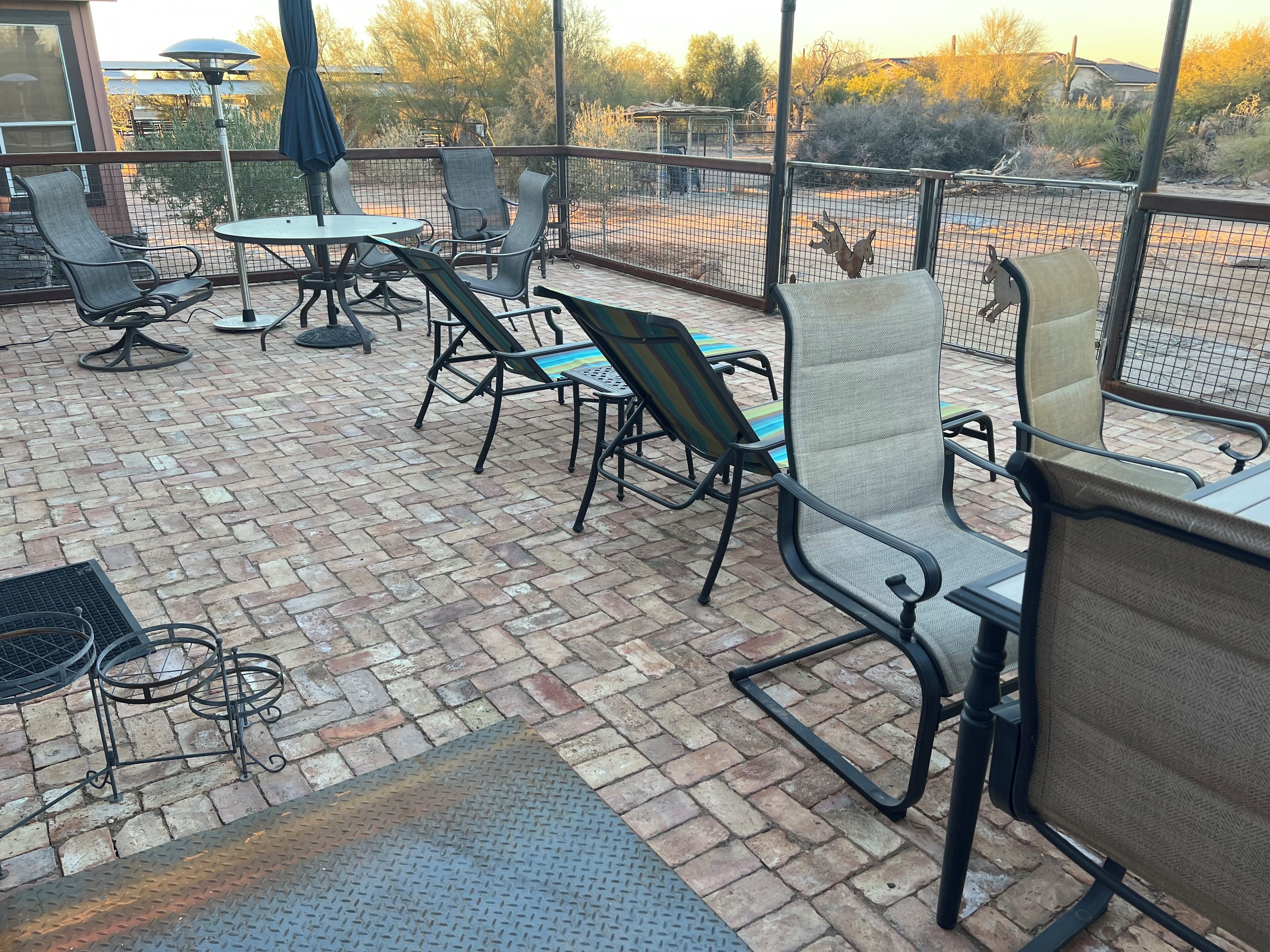 An outdoor patio with brick flooring, metal chairs, and tables.