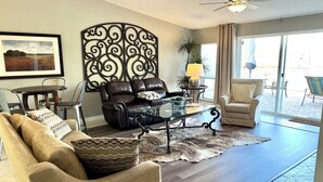A living room with a leather sofa, a glass coffee table, and a patterned rug.