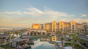 A resort with multiple buildings, a swimming pool, and a beach view.