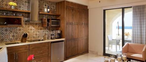 Une cuisine moderne avec des meubles en bois, un four à micro-ondes et un lave-vaisselle. Il y a un coin repas avec une table dressée pour deux personnes, ainsi qu’un balcon avec vue.