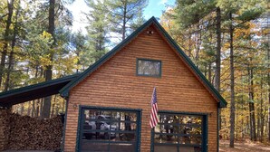 Une cabane en bois avec un toit à pignon, un garage doté d’une grande fenêtre et un drapeau américain.