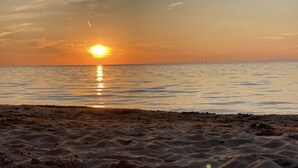 Une plage au coucher du soleil, avec un ciel dégagé et une mer calme.