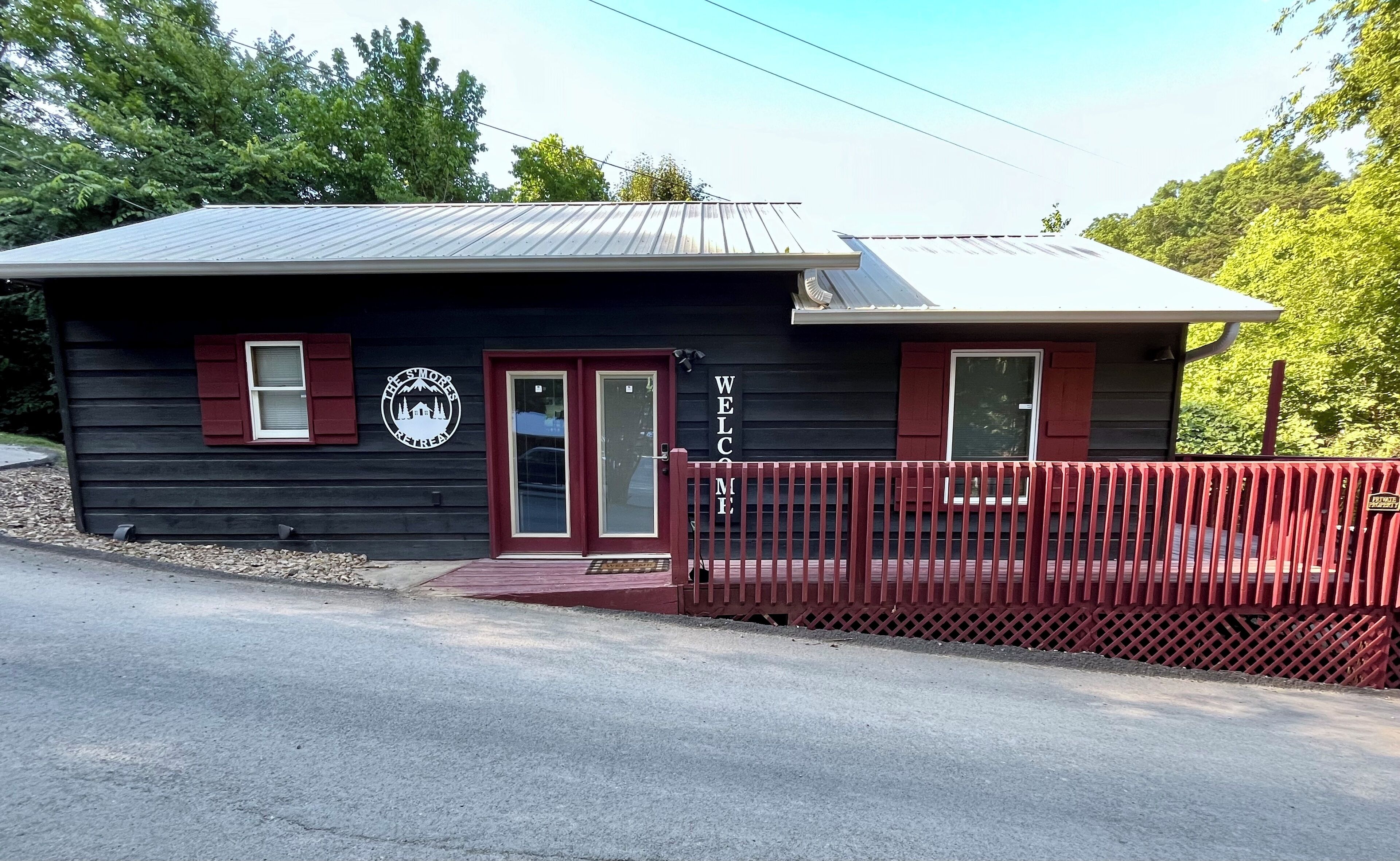 A small, two-story building with a black exterior and red accents, featuring a sign that reads "The Swoones Retreat" and a "Welcome" sign above the door.