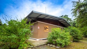 A small, single-story building with a sloped roof, surrounded by dense greenery. A sign on the building indicates it is part of a nature reserve. - Veragua Rainforest Lodge (Río Blanco)