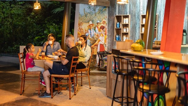 A group of people dining at an outdoor café with a mural in the background. - Veragua Rainforest Lodge (Río Blanco)