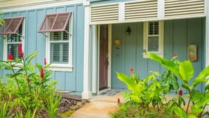 A house with a front porch, a door with a sign, and a window with shutters. - Princeville Paradise - Luxury A/C (Princeville)