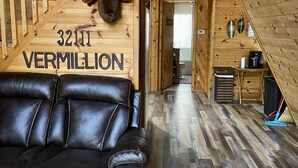 Een gezellig houten interieur met een leren bank, een trap en een keukenhoek.