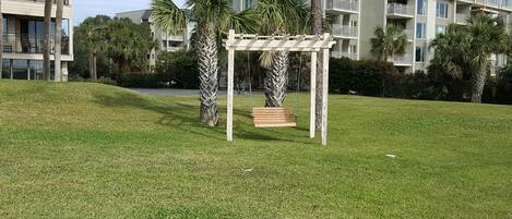 Une zone herbeuse avec une balançoire en bois et une pergola.
