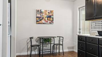 Une cuisine avec une table à manger, des chaises et un tableau accroché au mur.