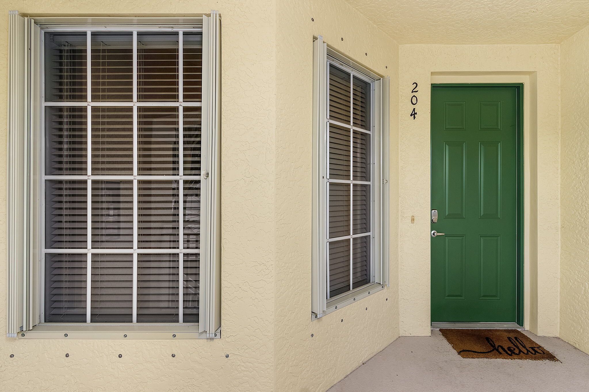 Fachada de edificio con dos ventanas y una puerta verde, cada una con un número encima.