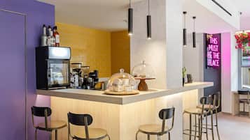 A modern kitchen with a bar area, featuring a coffee machine, a glass display case, and bar stools.