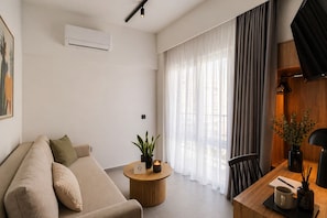 A modern living room with a sofa, a round wooden coffee table, a small plant, and a TV on a wooden stand.