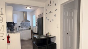 A modern kitchen with white cabinetry, a stainless steel refrigerator, a coffee machine, and a black countertop. - Modern Private Share Bedroom Bus stop to NYC (Englewood)