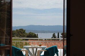 A balcony with a table and chairs, overlooking a body of water and distant mountains. - Barba Zoran 2 (Bol)