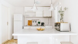 Een moderne keuken met witte kastjes, een marmeren eiland en hanglampen.