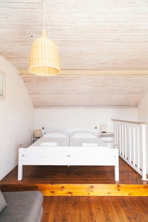 A bedroom with a white bed, wooden floor, and a hanging light fixture. - Barba Zoran 2 (Bol)