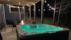 A hot tub with a control panel, surrounded by outdoor seating and string lights. - YES! 🎸FamilyPlace 🏊‍♀️POOL/WaterFall💦HOTTUB 🔥FIREPIT🎱POOLTABLE⚡EV🎡FUN❤️LUV (Branson)