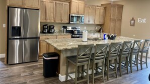 A modern kitchen with wooden cabinets, stainless steel appliances, and a central island with bar stools. - YES! 🎸FamilyPlace 🏊‍♀️POOL/WaterFall💦HOTTUB 🔥FIREPIT🎱POOLTABLE⚡EV🎡FUN❤️LUV (Branson)