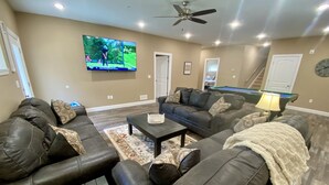 A living room with dark leather sofas, a pool table, and a television mounted on the wall. - ELITE📍nearSIGHTnSOUND 🏊‍♀️POOL/WaterFall💦HOTTUB ⚡EV 🔥FIREPIT 🎱POOLTABLE 🎡 (Branson)