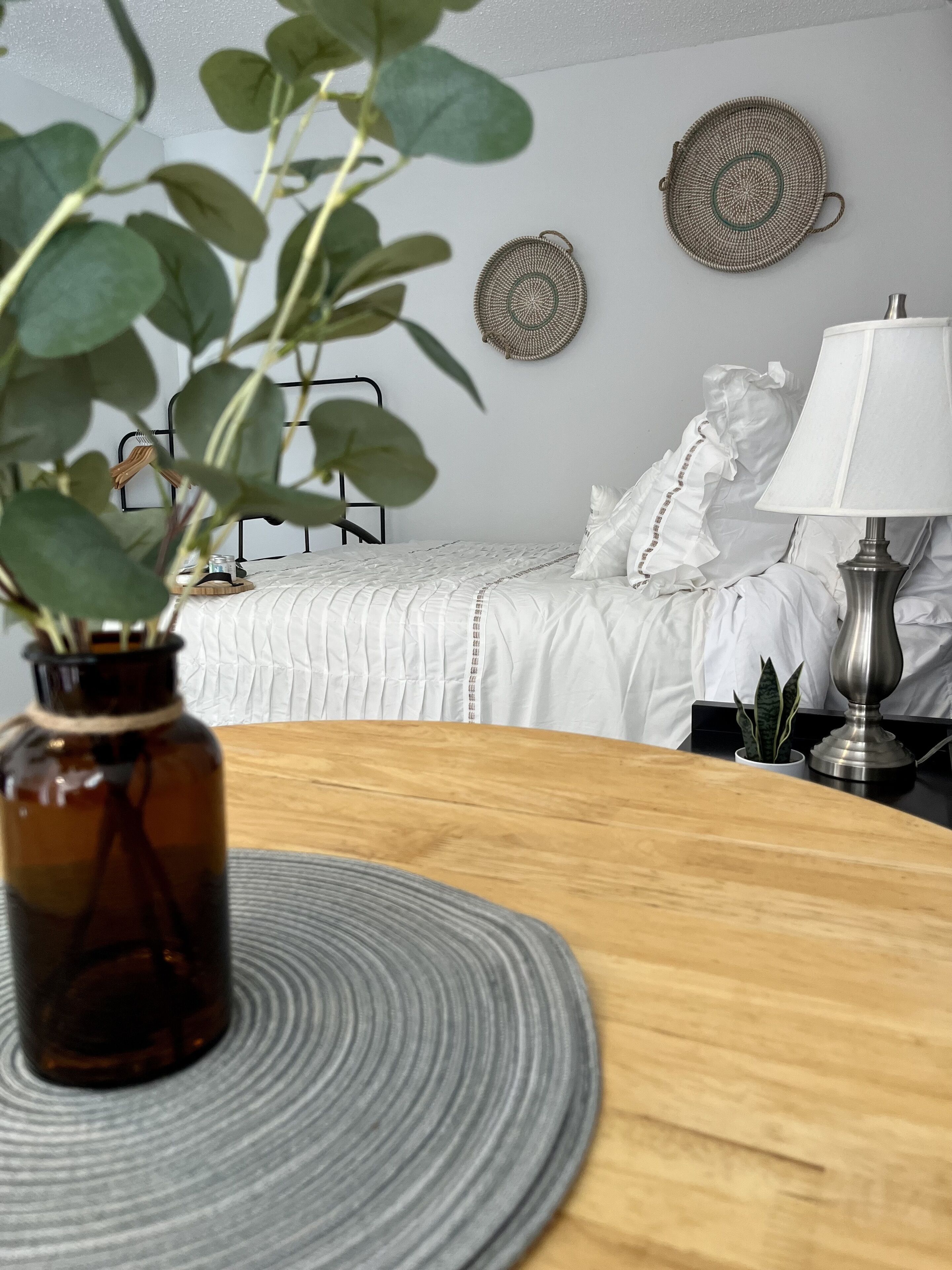 Ein ordentlich eingerichtetes Schlafzimmer mit Bett, Nachttisch, Lampe und dekorativen Wandbildern.