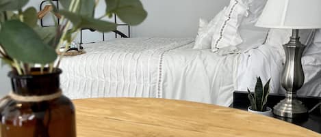 A neatly arranged bedroom with a bed, bedside table, lamp, and decorative wall hangings.