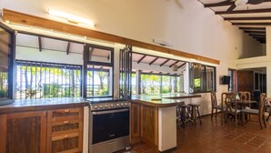 Une cuisine avec des meubles de rangement en bois, une cuisinière et un coin repas comprenant des chaises et une table.