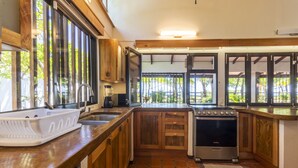 Une cuisine avec des meubles de rangement en bois, une cuisinière et une grande fenêtre.
