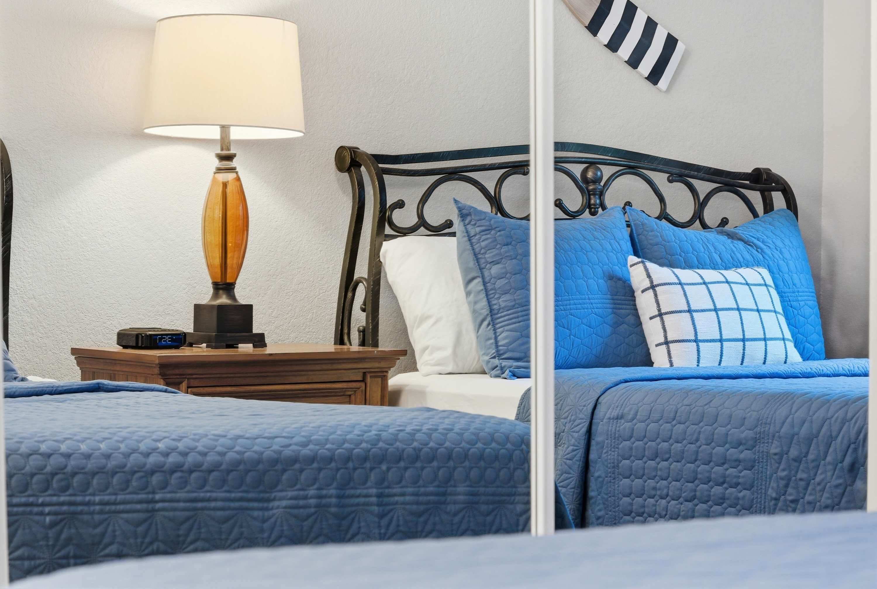 Un dormitorio con dos camas, una mesita de noche con lámpara y un reloj de pared.