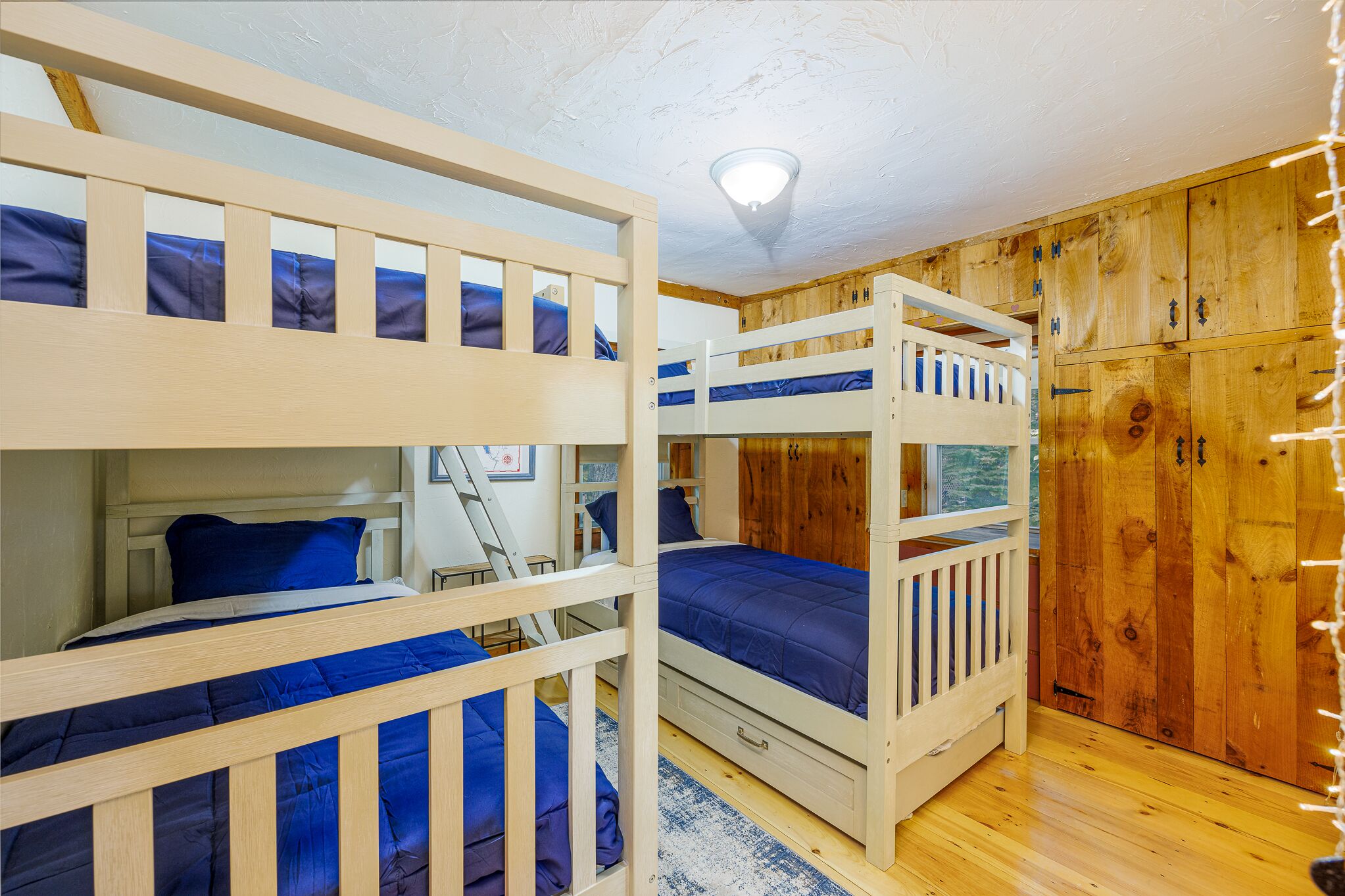 Une chambre avec des lits superposés, des murs en bois et un luminaire au plafond.