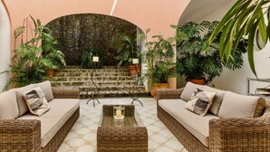 Eine Sitzecke mit Korbschaukel-Sofas, einem zentralen Couchtisch und einer Wand aus Stein.