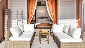 Ein Zimmer mit einem Bett, zwei weißen Sofas, einem kleinen Tisch und einem Korbstuhl.