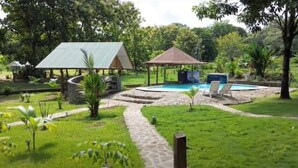 Un espace piscine agrémenté d’un belvédère, d’une structure couverte et d’un chemin en pierre.