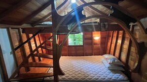 Une pièce chaleureuse, aménagée comme un chalet en bois, avec un lit, une fenêtre et un plafond en pente.