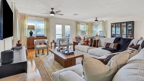 A spacious living room with a large sofa, a coffee table, and a television mounted on the wall.