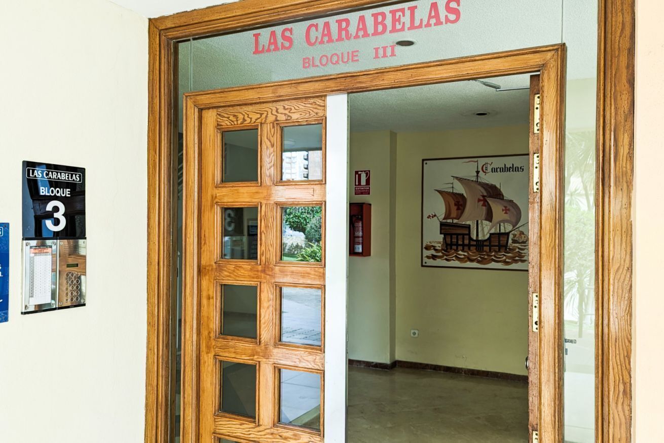 Een houten deur met ruitpanelen en een bord erboven waarop staat 'LAS CARABELAS BLOCUE III'.
