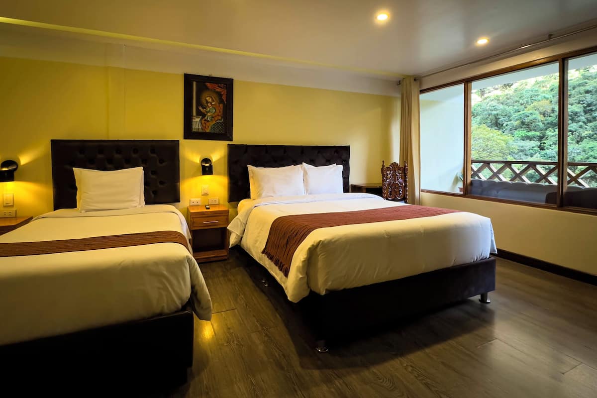 A hotel room with two beds, wooden flooring, a large window with a view of greenery, and a painting on the wall.
