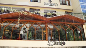 A hotel named Santuario with a covered outdoor area featuring a wooden structure and glass windows. - Santuario Machupicchu (Machu Picchu)